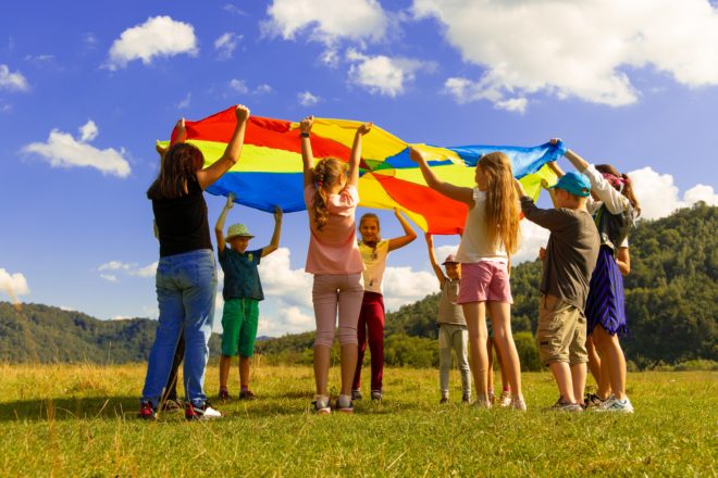 Group of Children Playing Outside with Coloured Sheet